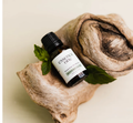 Essential oil bottle labeled 'essence one' on a piece of wood with leaves.